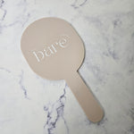 Oval handheld mirror in almond acrylic and white logo