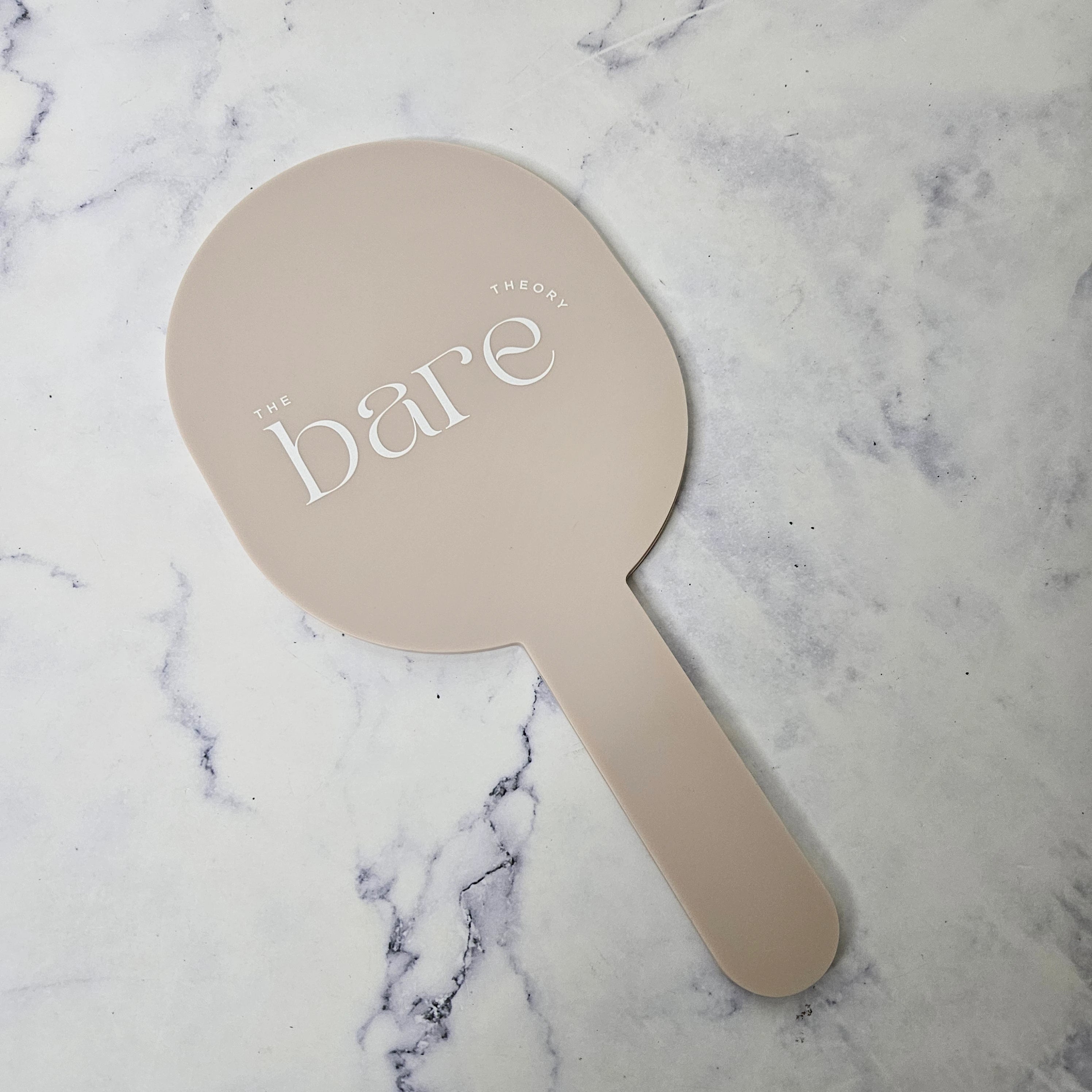 Oval handheld mirror in almond acrylic and white logo