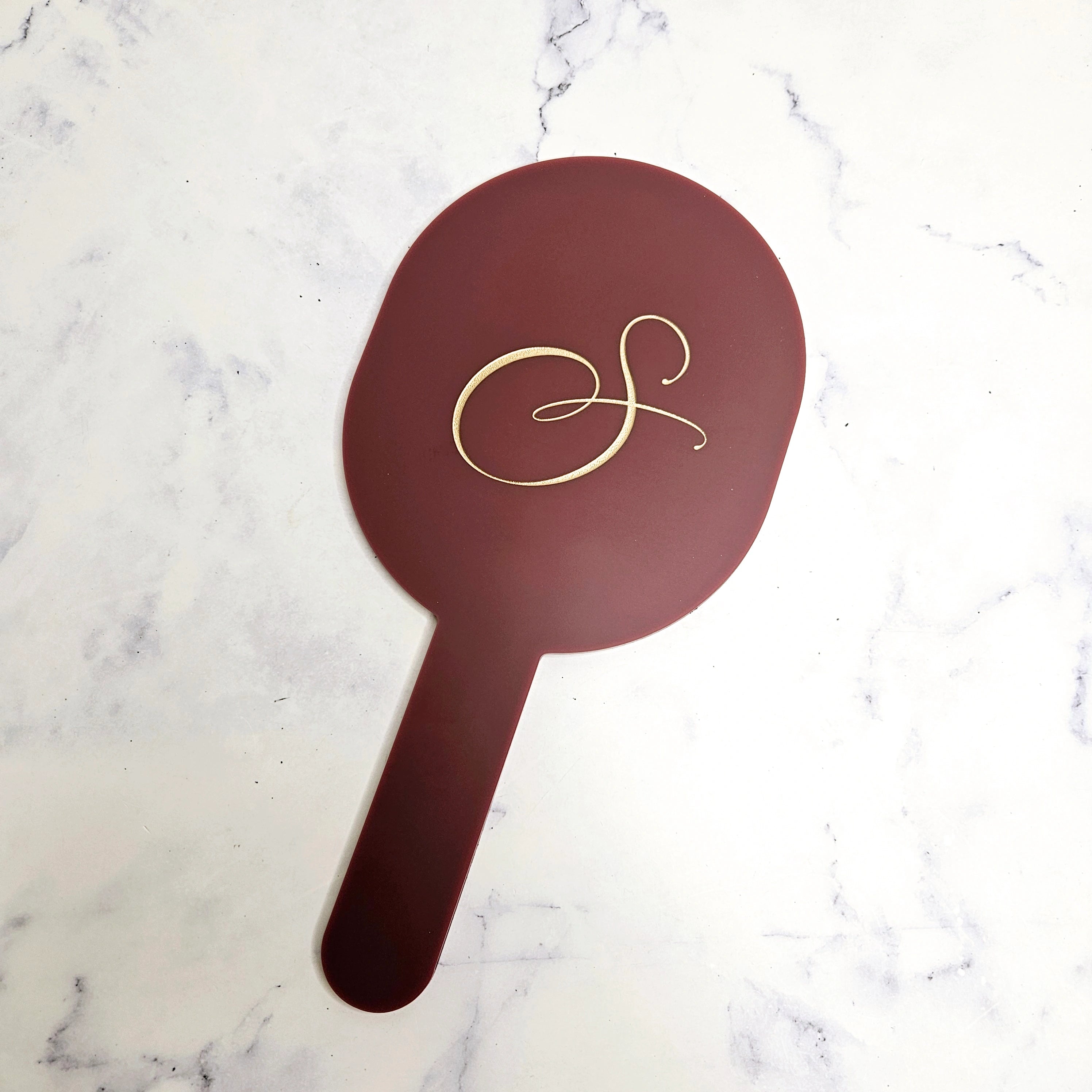 Oval handheld mirror with gold logo and cherry acrylic