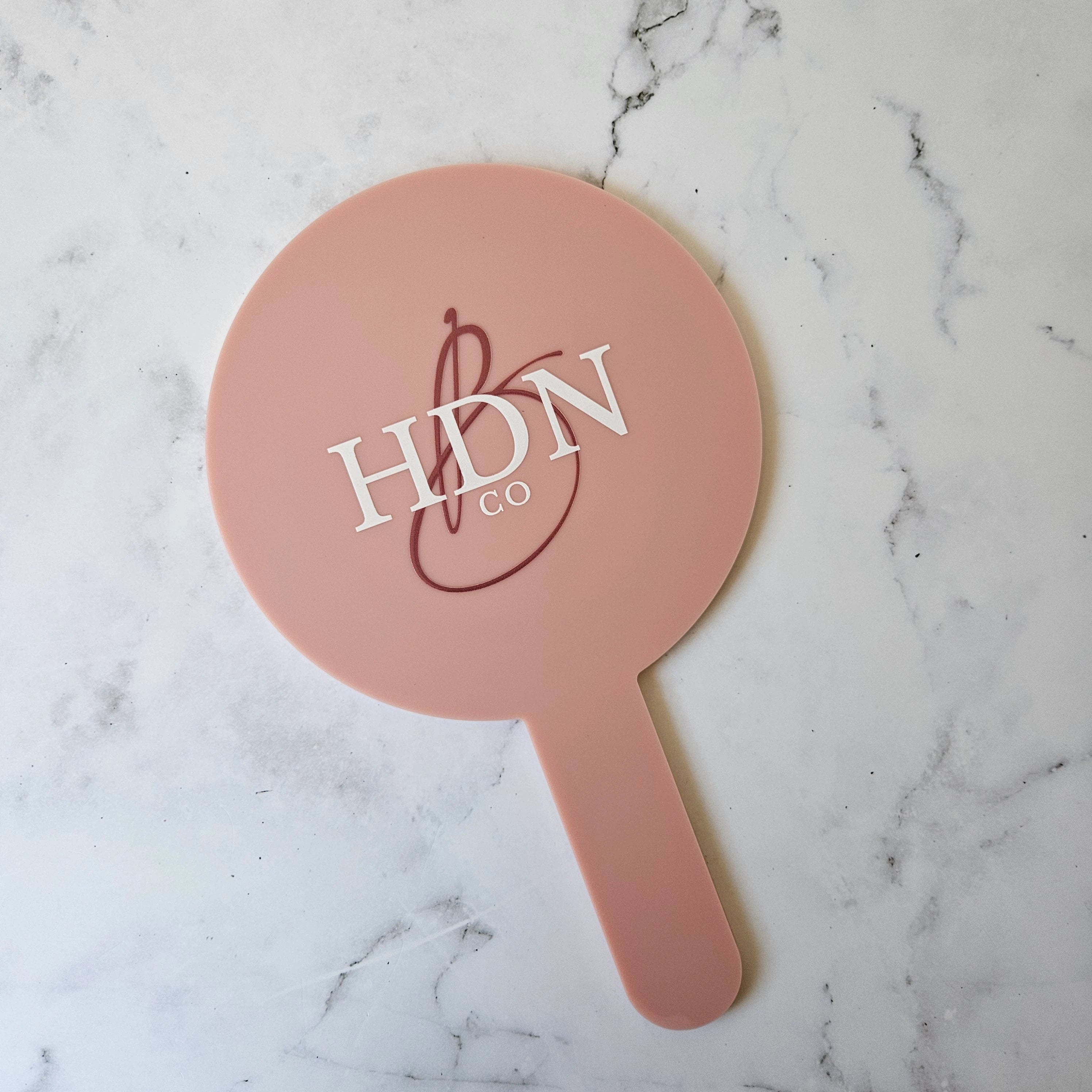 Round Handheld Mirror in Pink Clay Acrylic with multi-colour Logo